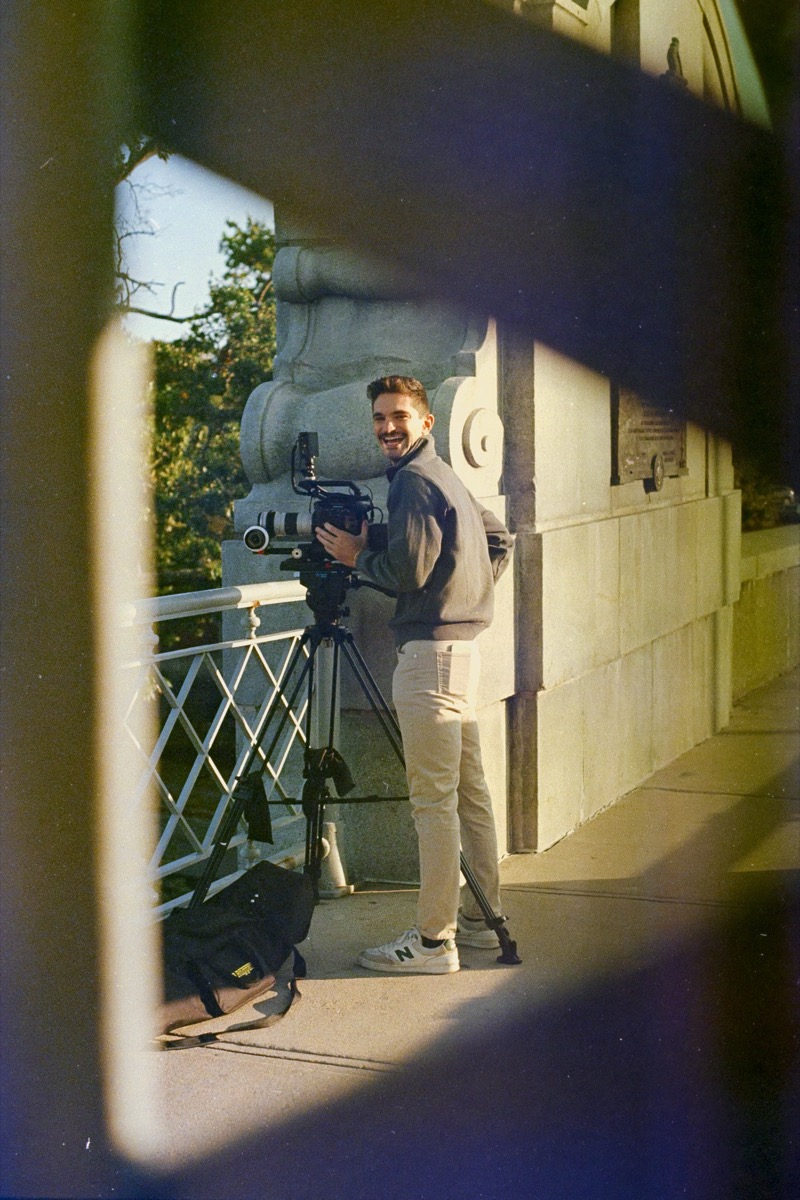 Michael Rotiroti on location with cinema camera and tripod, framed through doorway