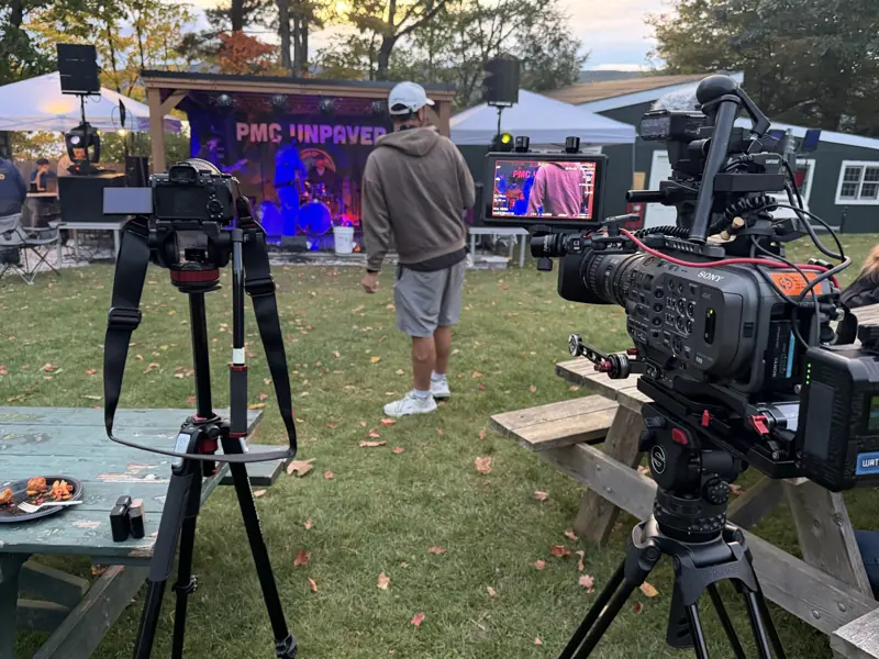 A Sony FX9 on a tripod locked on the PMC Unpaved stage by the lake before dark