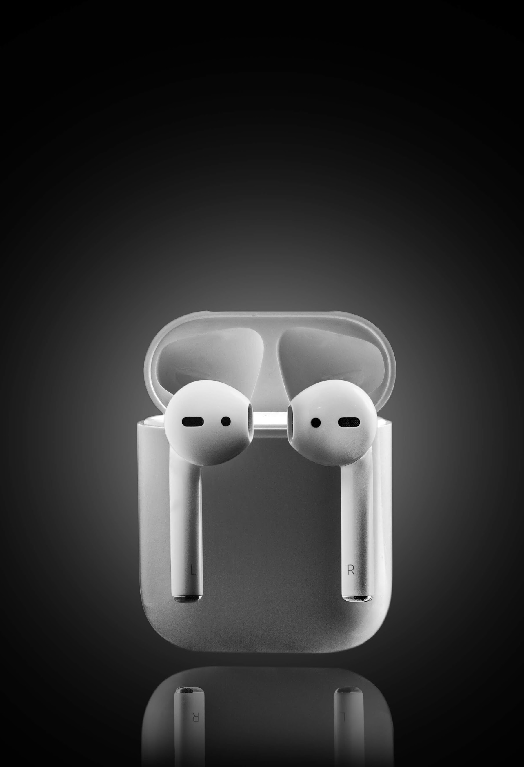 White AirPods in open charging case against dark gradient background