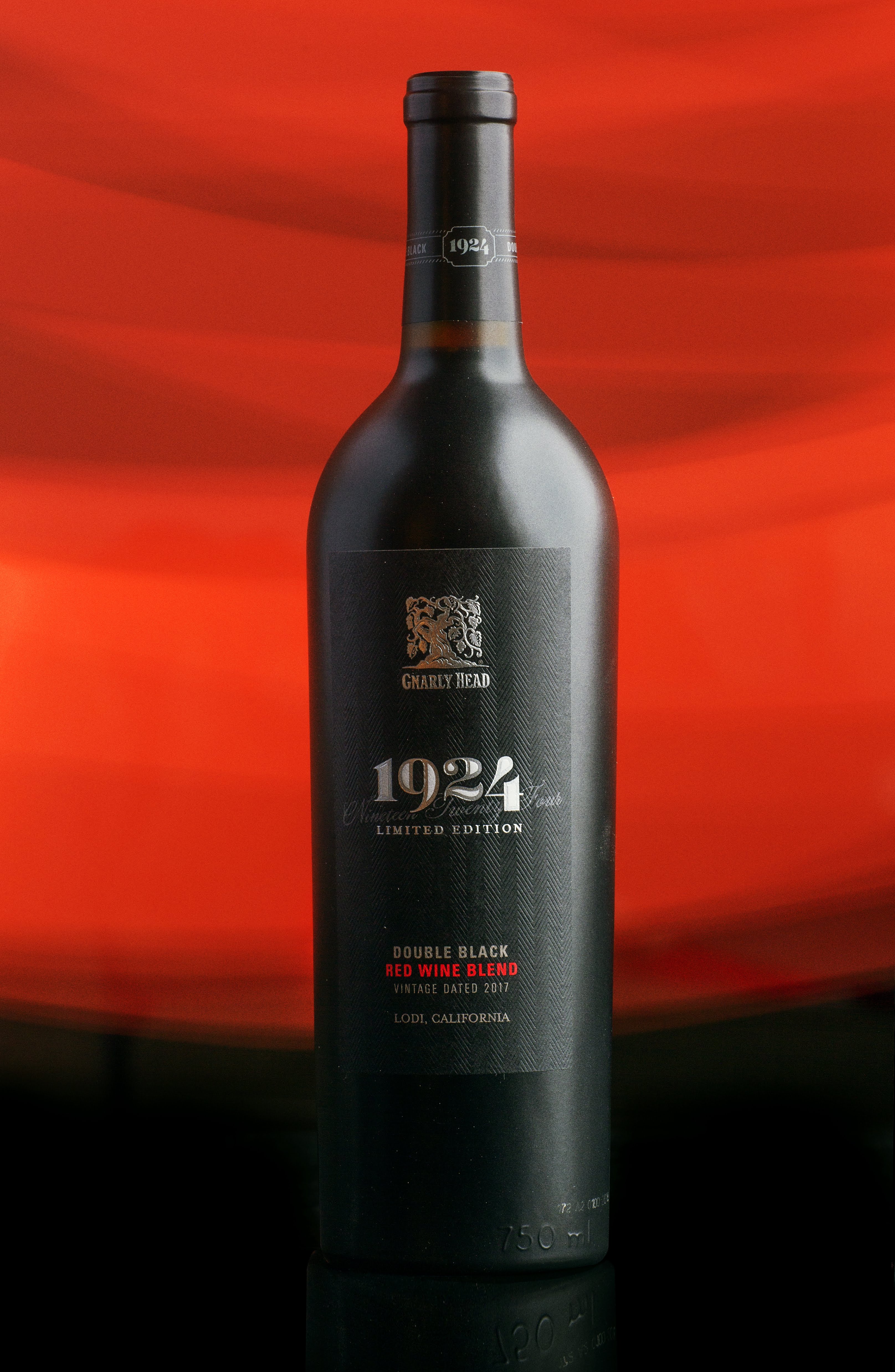 Gnarly Head 1924 red wine bottle on reflective surface with red backdrop